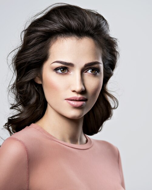 Portret van brunette vrouw met mooi lang bruin haar. Vrij jong volwassen meisje poseren in de studio. Close-up aantrekkelijk vrouwelijk gezicht.