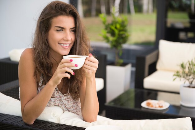 Portret van charmante jonge vrouw op terras koffie drinken