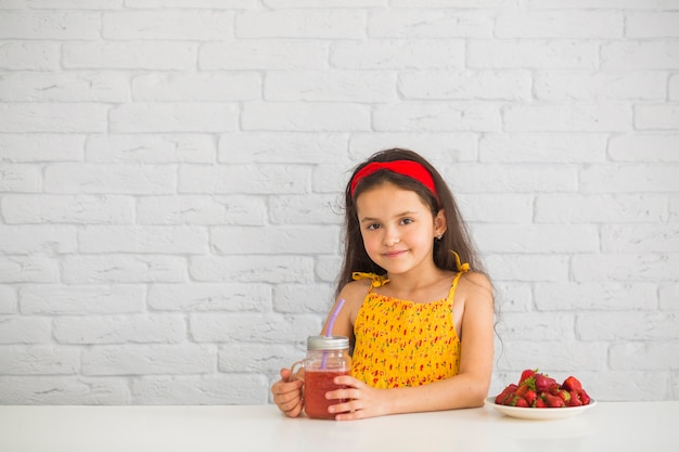 Portret van de aardbei van de meisjesholding smoothies in kruik