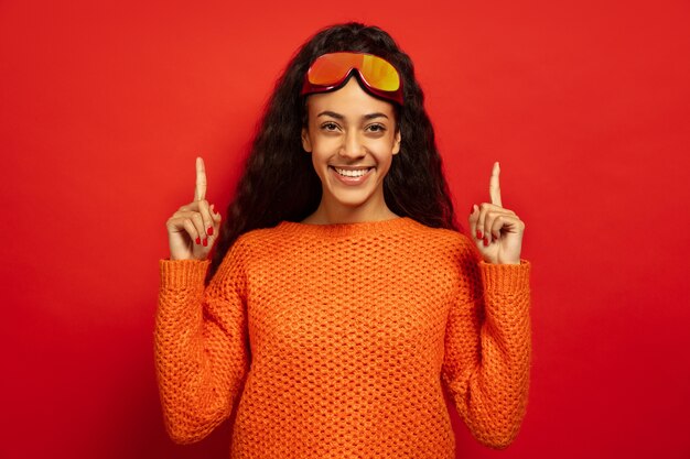 Portret van de Afro-Amerikaanse jonge brunette vrouw in skimasker op rode ruimte