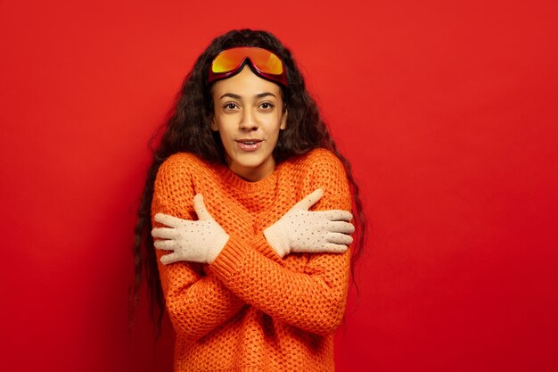 Portret van de Afro-Amerikaanse jonge brunette vrouw in skimasker op rood