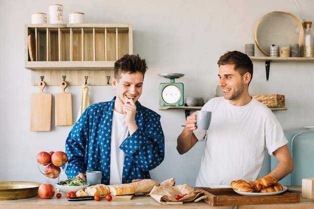 Portret van de gelukkige jonge mens twee die ontbijt in keuken voorbereidt