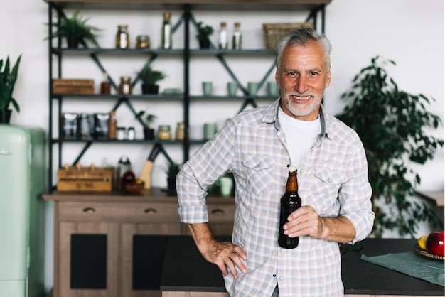 Portret van de glimlachende hogere mens die zich in het bierfles van de keukenholding bevinden