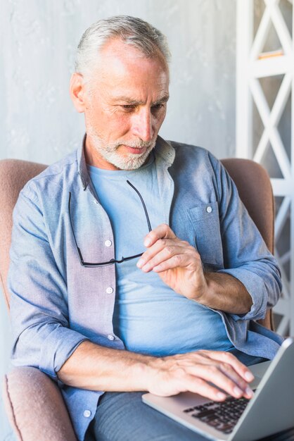 Portret van de hogere mens die laptop met behulp van