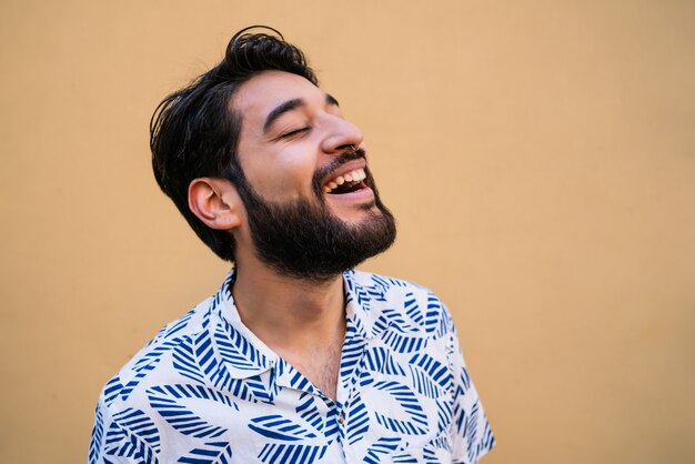 Portret van de jonge knappe man die van de zomer geniet en de zomerkleren draagt tegen geel.