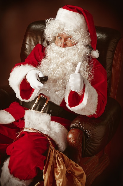 Portret van de kerstman in rood kostuum met tv-afstandsbediening