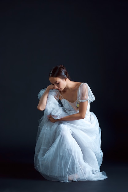 Portret van de klassieke ballerina in witte jurk op zwart