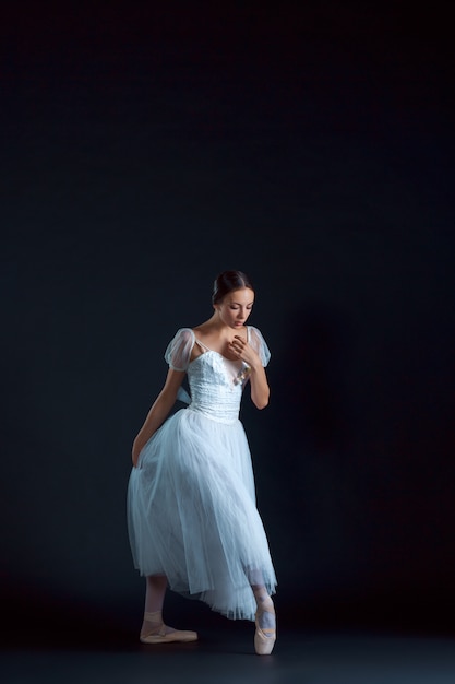 Portret van de klassieke ballerina in witte jurk op zwart