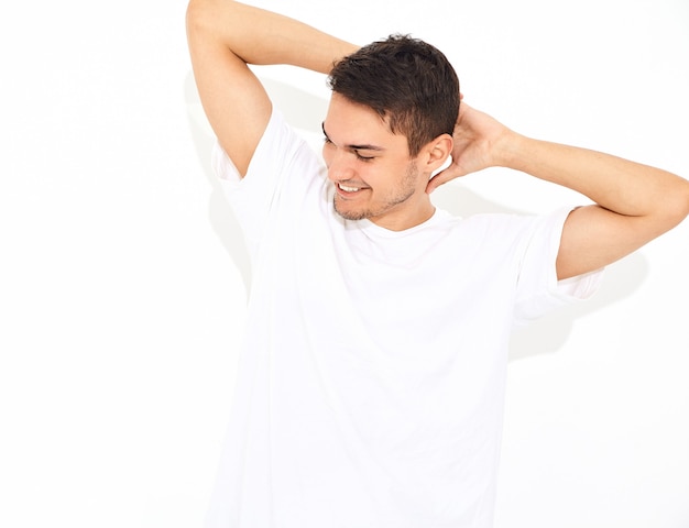 Portret van de knappe glimlachende jonge modelmens gekleed in jeanskleren en T-shirt het stellen. Zijn hoofd aanraken