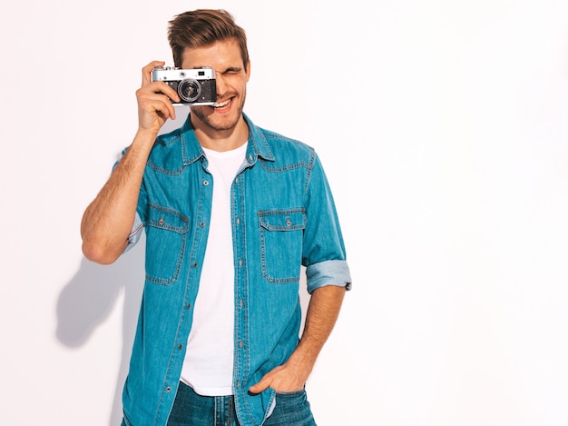 Portret van de knappe glimlachende mens die de kleren van de zomerjeans draagt. Model man met vintage fotocamera.