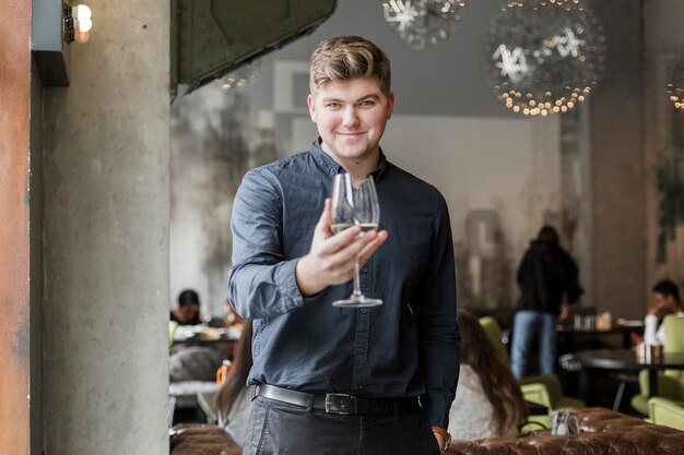 Portret van de positieve jonge mens die een glas wijn houdt