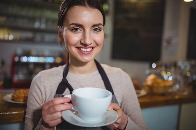 Portret van de serveerster die kopje koffie