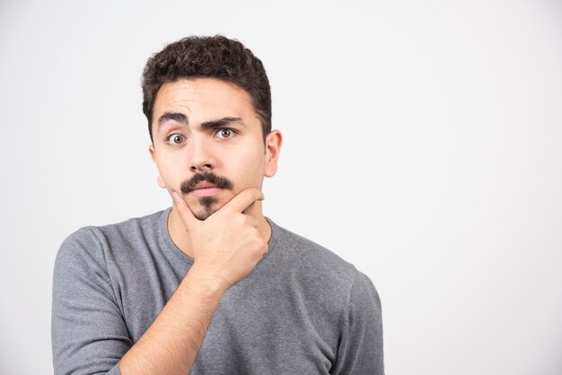 Portret van doordachte jonge man die door de muur.