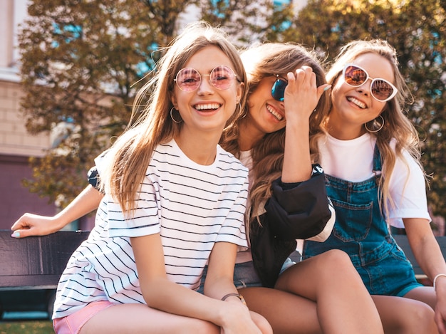 Portret van drie jonge mooie glimlachende hipster meisjes in trendy zomerkleren. Sexy zorgeloze vrouwen die zich voordeed op straat. Positieve modellen met plezier in een zonnebril