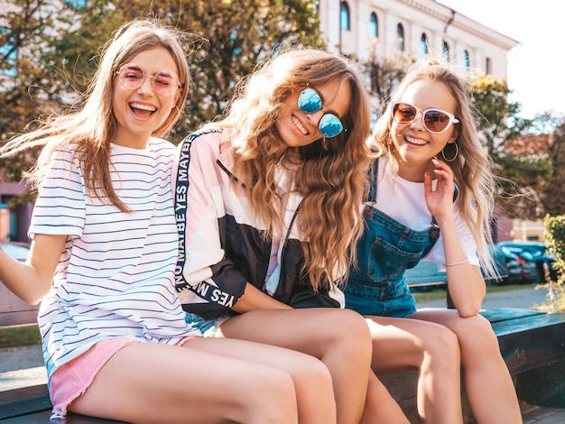 Portret van drie jonge mooie glimlachende hipster meisjes in trendy zomerkleren. sexy zorgeloze vrouwen die zich voordeed op straat. positieve modellen met plezier in een zonnebril