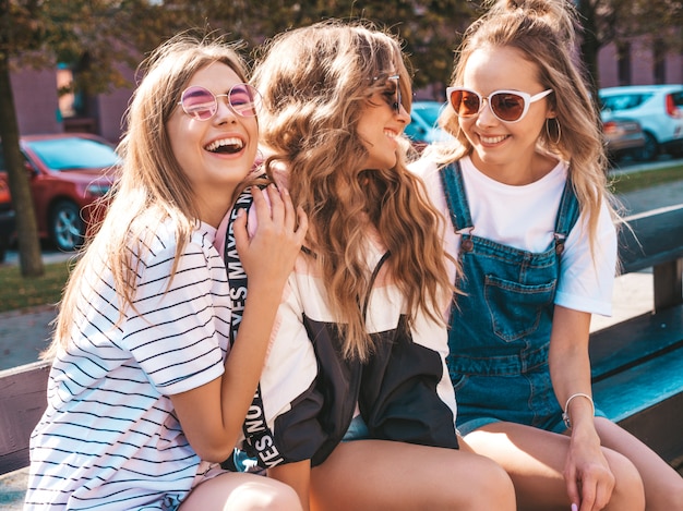 Portret van drie jonge mooie glimlachende hipster meisjes in trendy zomerkleren. Sexy zorgeloze vrouwen die zich voordeed op straat. Positieve modellen met plezier in een zonnebril