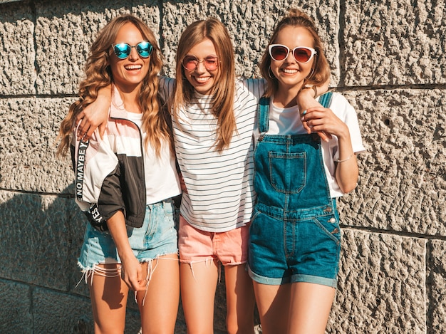 Portret van drie jonge mooie glimlachende hipster meisjes in trendy zomerkleren. sexy zorgeloze vrouwen die zich voordeed op straat. positieve modellen met plezier in een zonnebril