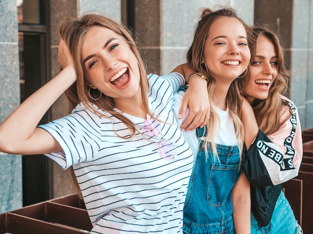 Portret van drie jonge mooie glimlachende hipster meisjes in trendy zomerkleren. Sexy zorgeloze vrouwen die zich voordeed op straat. Positieve modellen met plezier
