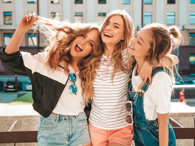 Portret van drie jonge mooie glimlachende hipster meisjes in trendy zomerkleren. Sexy zorgeloze vrouwen die zich voordeed op straat. Positieve modellen plezier maken