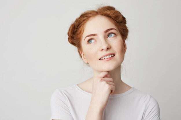 Portret van dromerige jonge mooi meisje met rood haar denken dromen aanraken van kin.