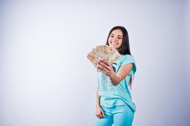 Portret van een aantrekkelijk meisje in blauwe of turquoise t-shirt en broek poseren met veel geld in haar hand