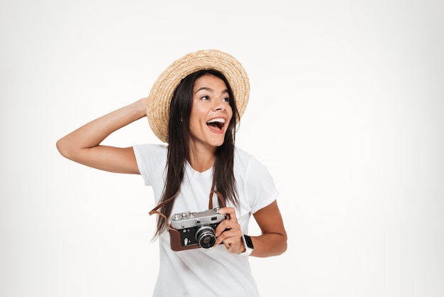 Portret van een aantrekkelijke vrouw die in hoed een camera houdt