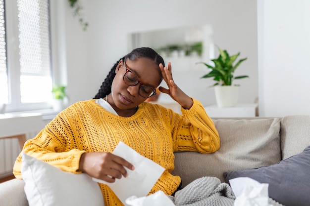 Portret van een aantrekkelijke vrouw die thuis op een bank zit met hoofdpijn die pijn voelt en met een uitdrukking van onwel zijn Verstoorde depressieve vrouw die op de bank ligt en sterke hoofdpijn voelt migraine