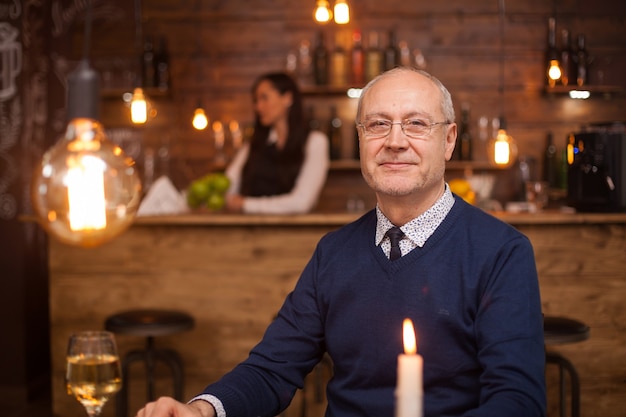 Portret van een aardige oude man die lacht naar de camera in een restaurant. man van in de zestig. volwassen mens.