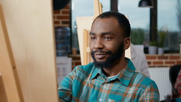 Portret van een afro-amerikaanse man die op canvas tekent in de kunstles, met aandacht voor inspiratiemodel en leraar. artistieke les in workshop om te leren hoe je professioneel schetsontwerp kunt tekenen.