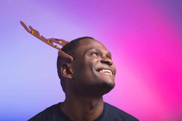 Portret van een afro-amerikaanse man draagt rudolph hertenhoorns en geniet van zijn accessoire voor kerstavond