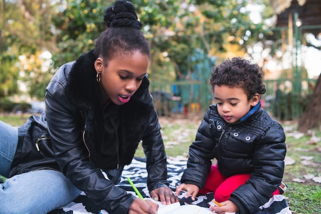 Portret van een Afro-Amerikaanse moeder met zijn zoon spelen en plezier samen buiten in het park. Monoparentale familie.