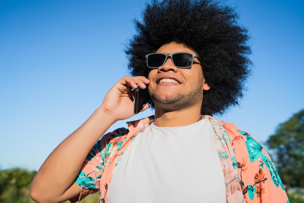 Portret van een afro-latijnse man die aan de telefoon praat terwijl hij buiten op straat staat