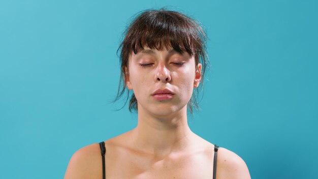 Portret van een atletische vrouw die ademt en ontspant na een training, zittend met gesloten ogen voor de camera. Actieve persoon die diep ademhaalt om te herstellen van gymnastiek.