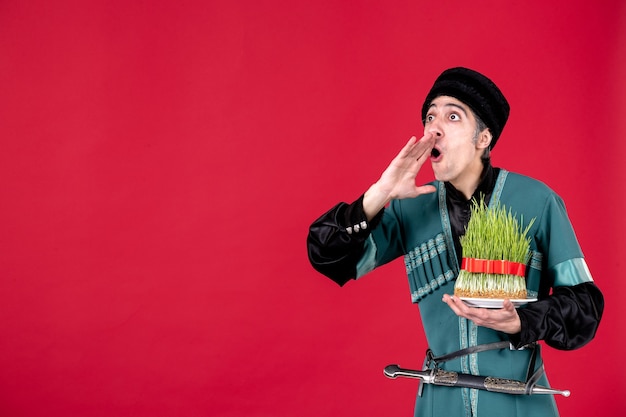 Portret van een azeri-man in traditionele klederdracht die groene semeni vasthoudt op de rode danser etnische novruz lente