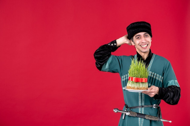 Portret van een azeri-man in traditionele klederdracht die semeni vasthoudt op de rode etnische danseres van de novruz lente