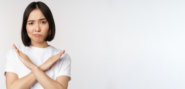 Portret van een aziatische koreaanse vrouw die een gebaar van een stopverbod laat zien met een arm kruisteken dat in t . staat