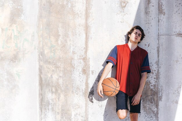 Portret van een basketbalspeler die op muur leunt