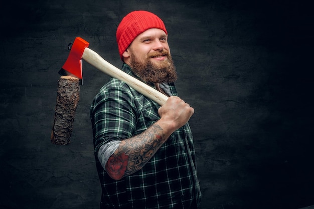 Portret van een bebaarde houthakker gekleed in een groen shirt houdt de rode bijl vast.