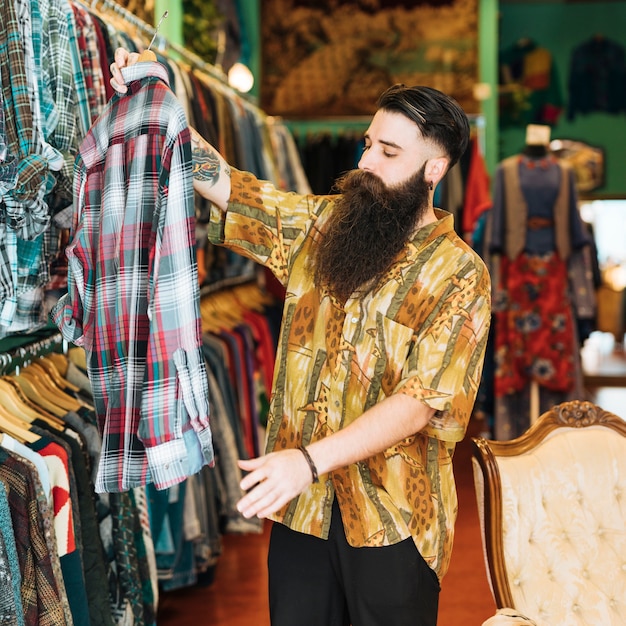 Portret van een bebaarde man kijken plaid shirt in kledingwinkel