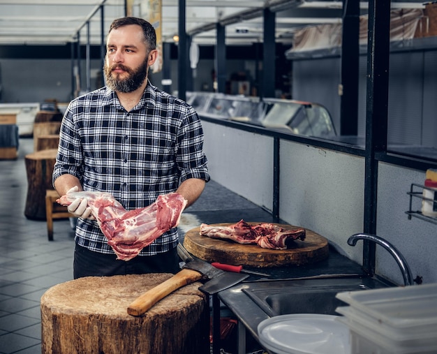 Gratis foto portret van een bebaarde slager in een slagerij
