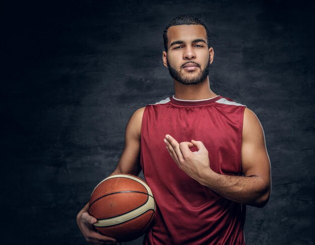 Portret van een bebaarde zwarte man houdt een basketbal vast.