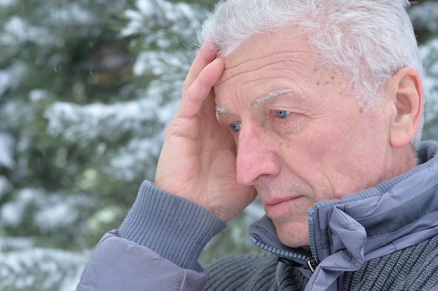 Portret van een bedachtzame senior man in een besneeuwd winterpark