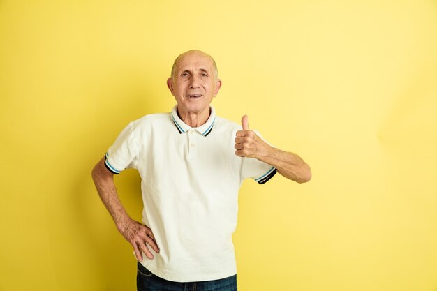 Portret van een blanke senior man geïsoleerd op gele studio achtergrond