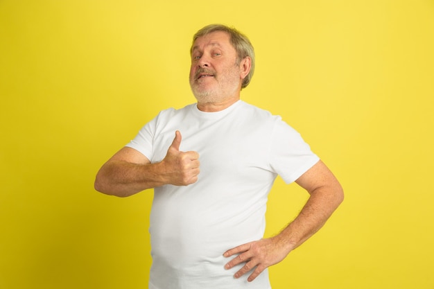 Portret van een blanke senior man geïsoleerd op gele studio muur