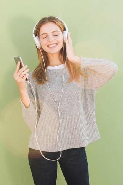 Portret van een blonde jonge vrouw die van de muziek op hoofdtelefoon geniet