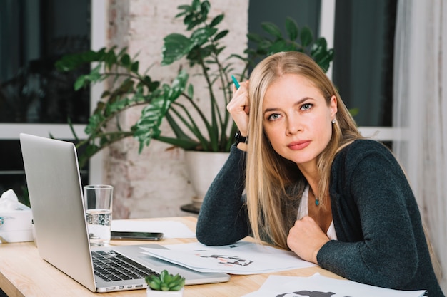 Portret van een blonde jonge vrouwelijke psycholoog met rorschach inkblot-testdocument en laptop