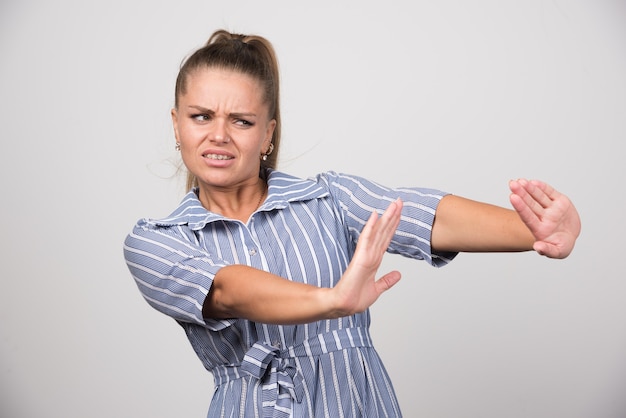 Portret van een boze vrouw die iets op een grijze muur afwijst.