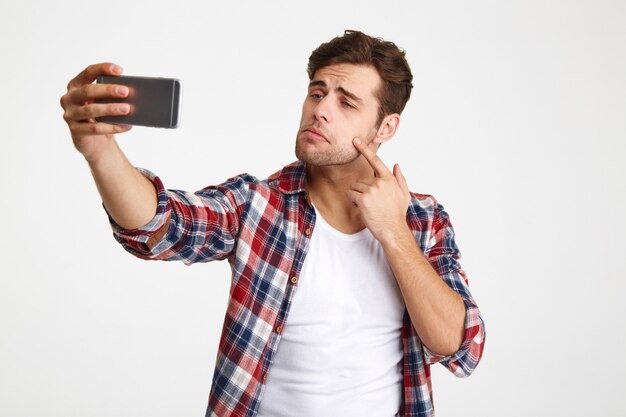 Portret van een casual jonge man die een selfie neemt