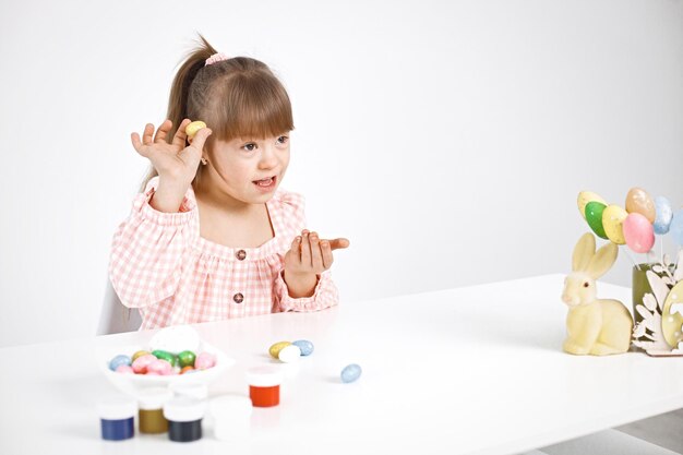 Portret van een charmant meisje met het syndroom van Down spelend met gekleurde paaseieren