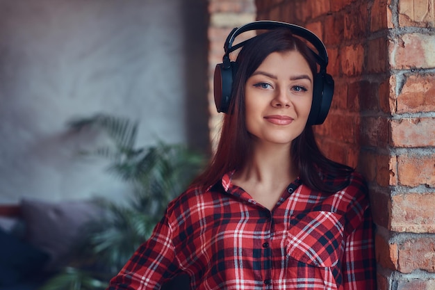 Portret van een charmante brunette in een flanellen hemd en jeans lis